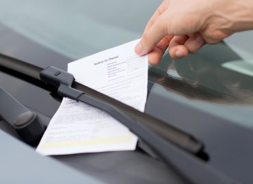 transportation and vehicle concept - parking ticket on car windscreen